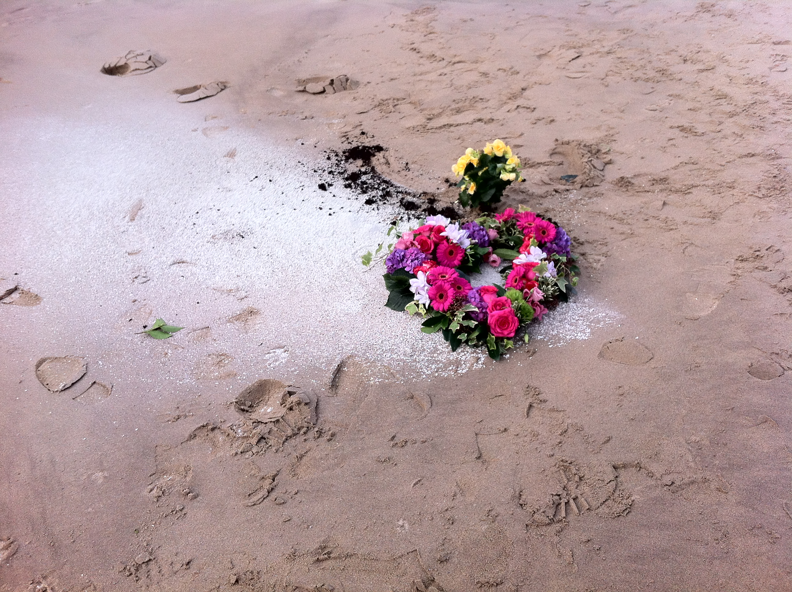 Funeral wreath lain on top of ashes scattered on the beach